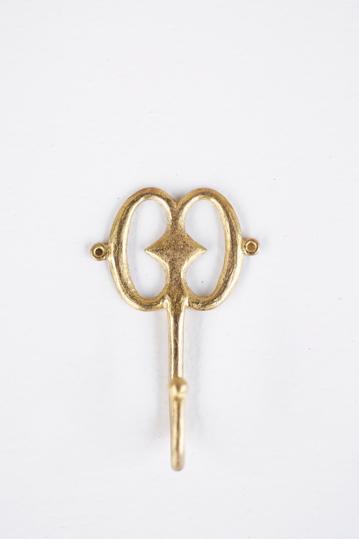 Brass decorative hook on a white background