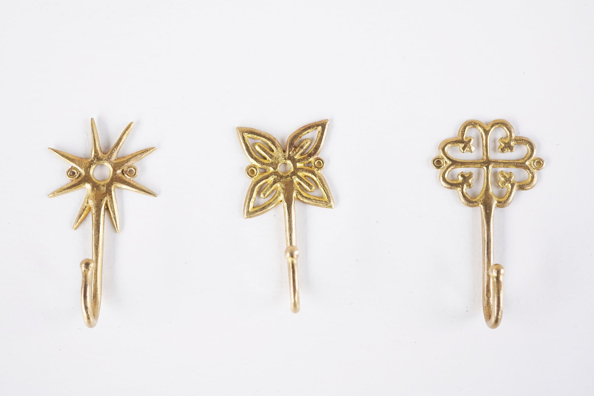 Set of brass decorative hooks on a white background