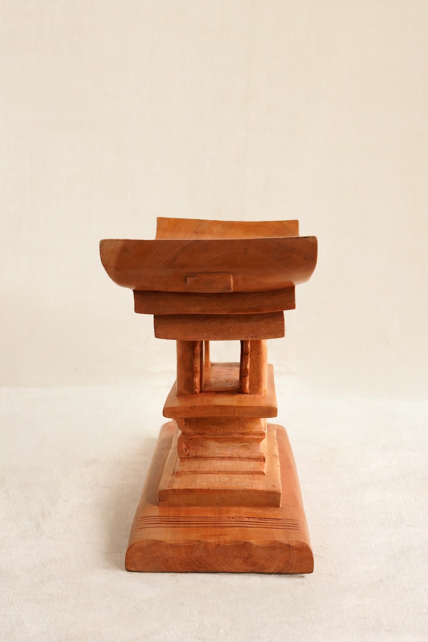 The side profile of a wooden stool showing a stack of books on  a beige background