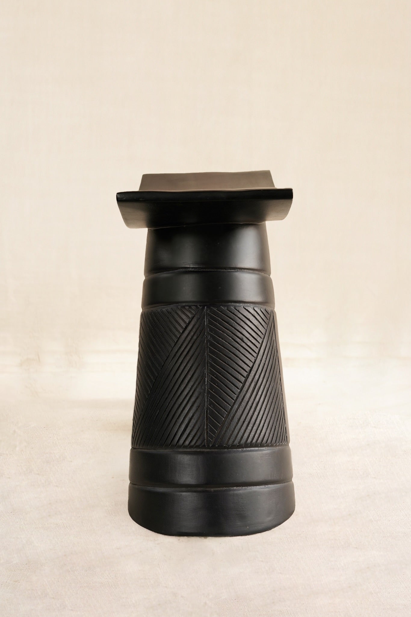 Black textured stool on a beige background