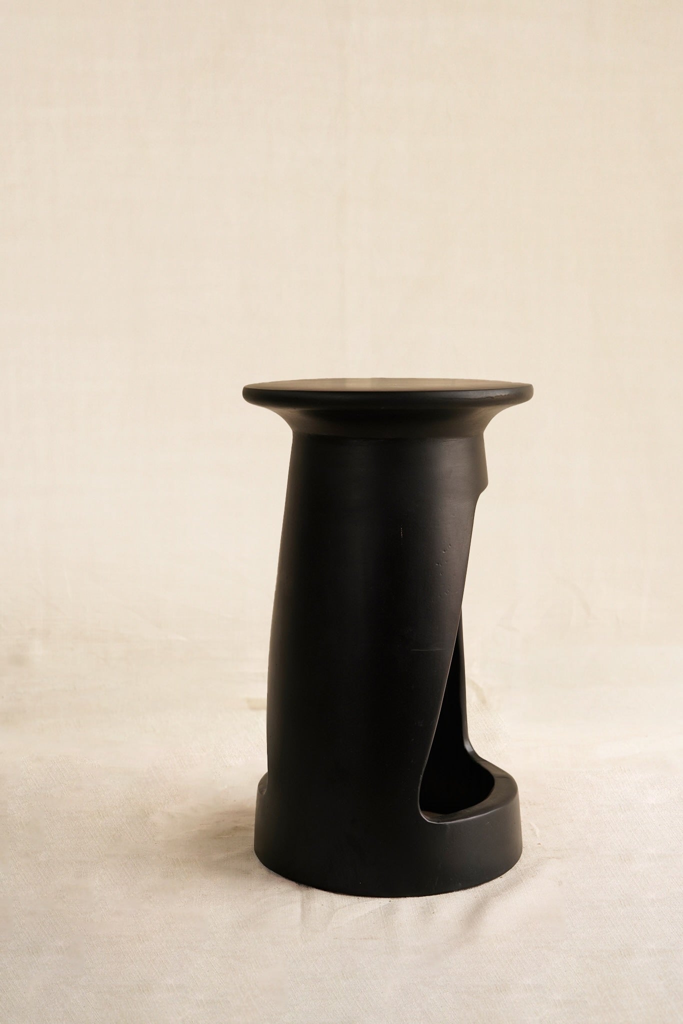 Black cylindrical stool on a beige background