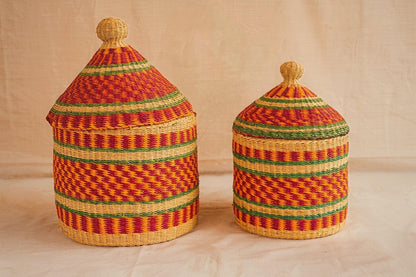 Two handwoven Bolga storage baskets in red, green, and beige patterns with leather-wrapped handles.