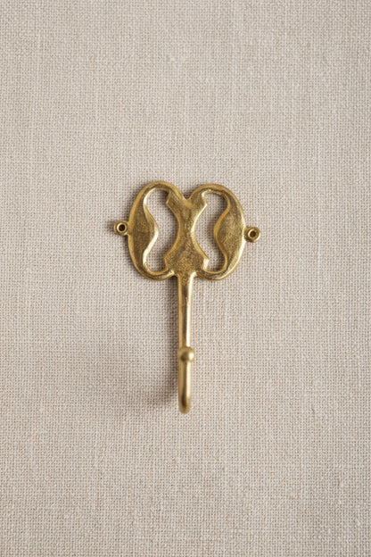 Brass decorative hook on a linen background
