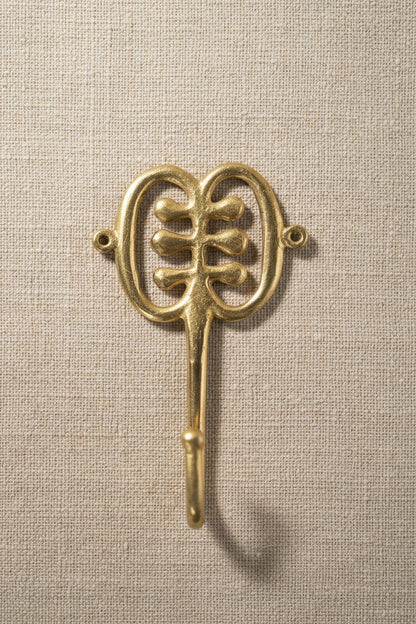 Brass decorative hook on a linen background