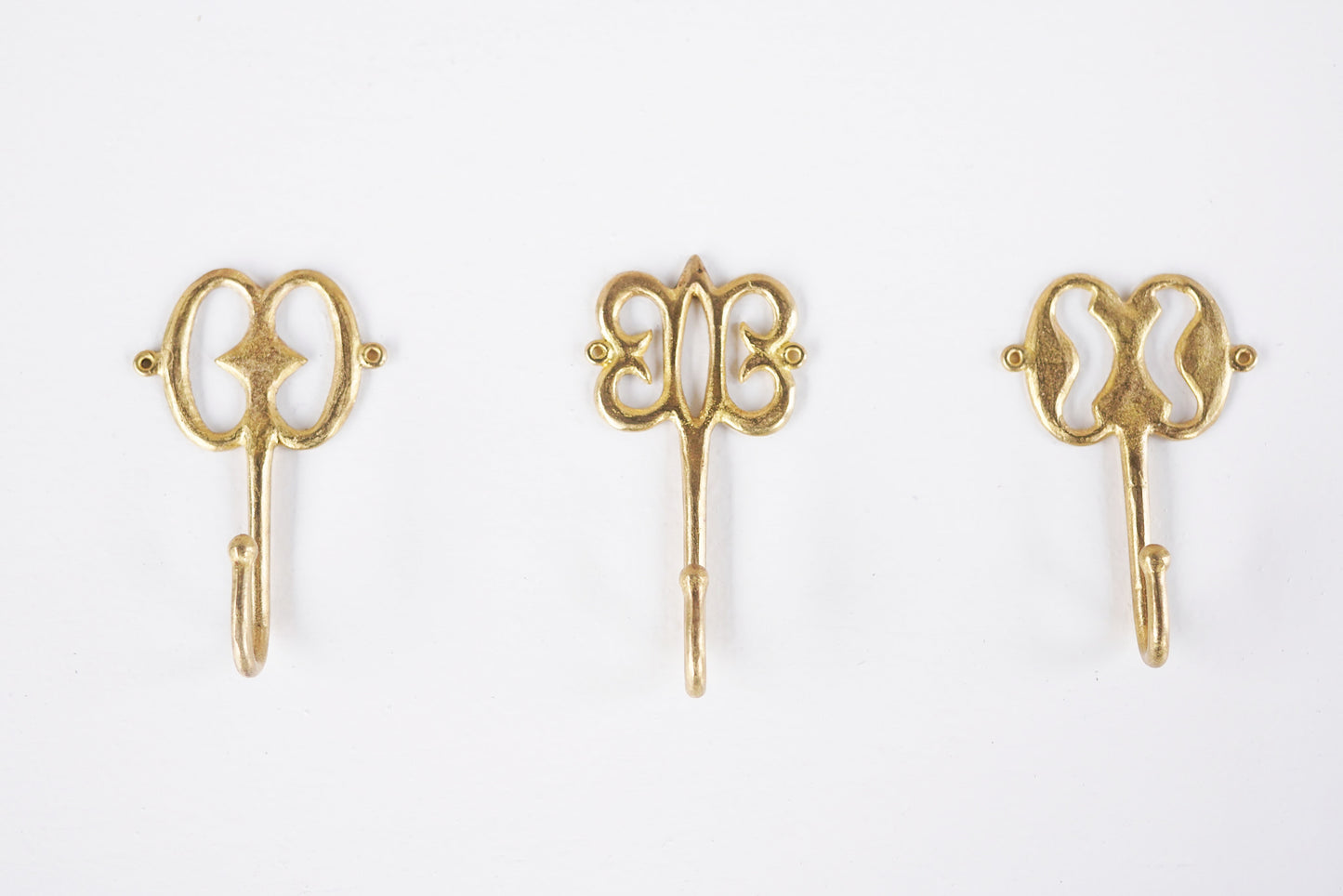 Set of brass decorative hooks on a white background