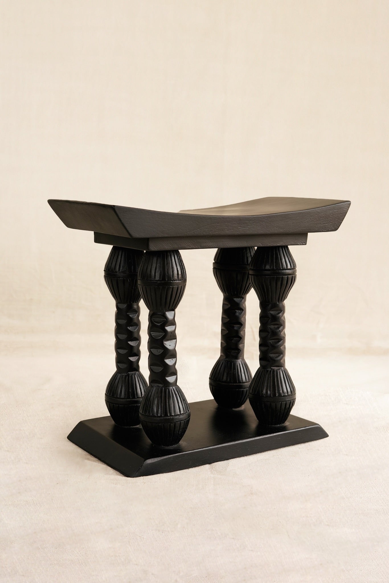 Decorative black stool with twisted legs on a beige background