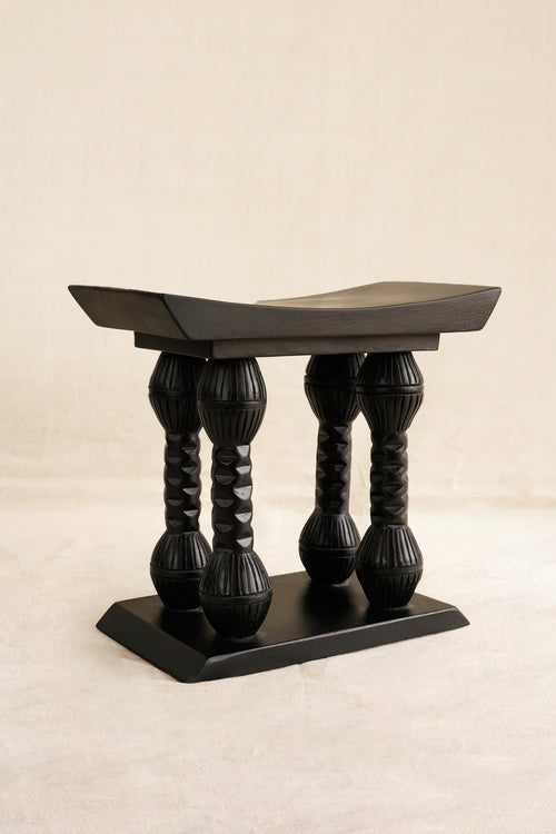 Decorative black stool with twisted legs on a beige background