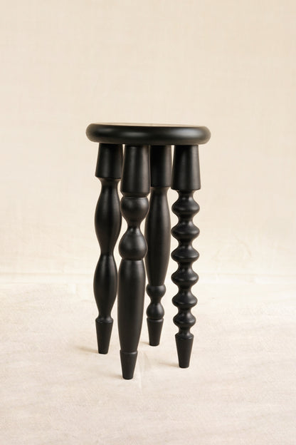 Black wooden stool with spiral legs on a beige background