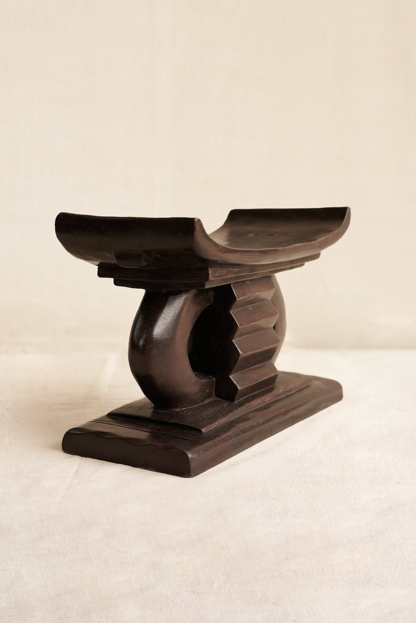 Miniature Wooden Ashanti stool with a decorative design on a beige background