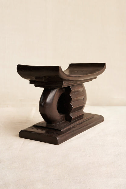 Miniature Wooden Ashanti stool with a decorative design on a beige background