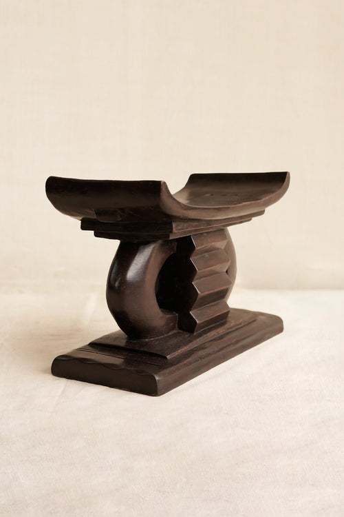 Miniature Wooden Ashanti stool with a decorative design on a beige background