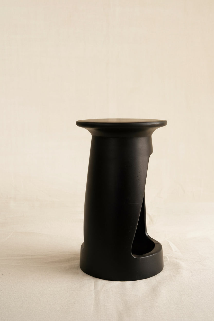 Black cylindrical stool on a beige background