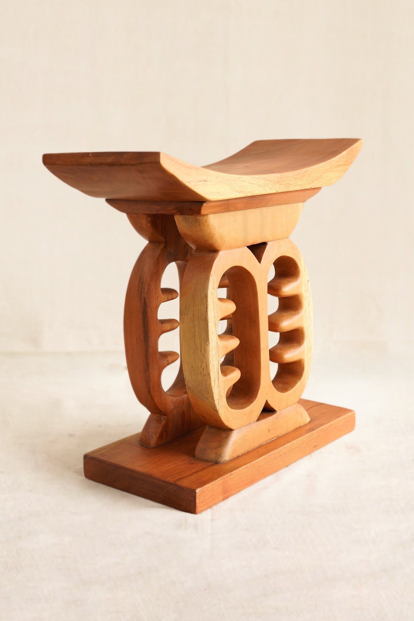Wooden stool with intricate design on a beige background