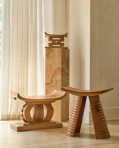 Three wooden stools of different designs on a light wood floor with a neutral wall background.